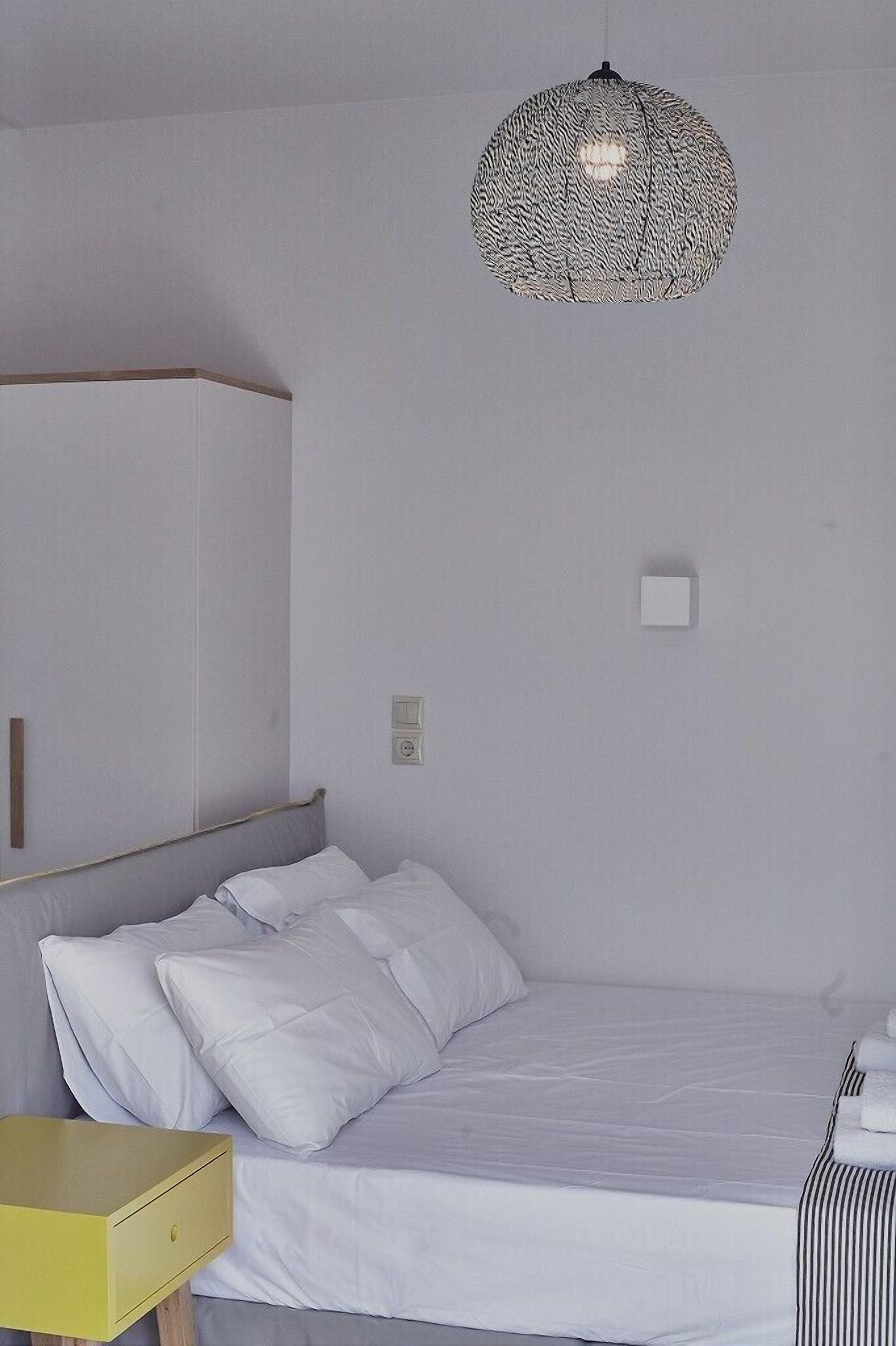 Un dormitorio con cama, mesita de noche, armario y lámpara colgante.