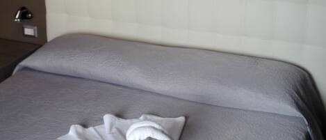 Una habitación de hotel con cama, cabecera blanca y un cuadro de un muelle en la pared.