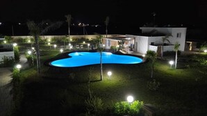 A swimming pool surrounded by a landscaped garden with pathways and lighting. - Samanà Bed (Porto Cesareo)
