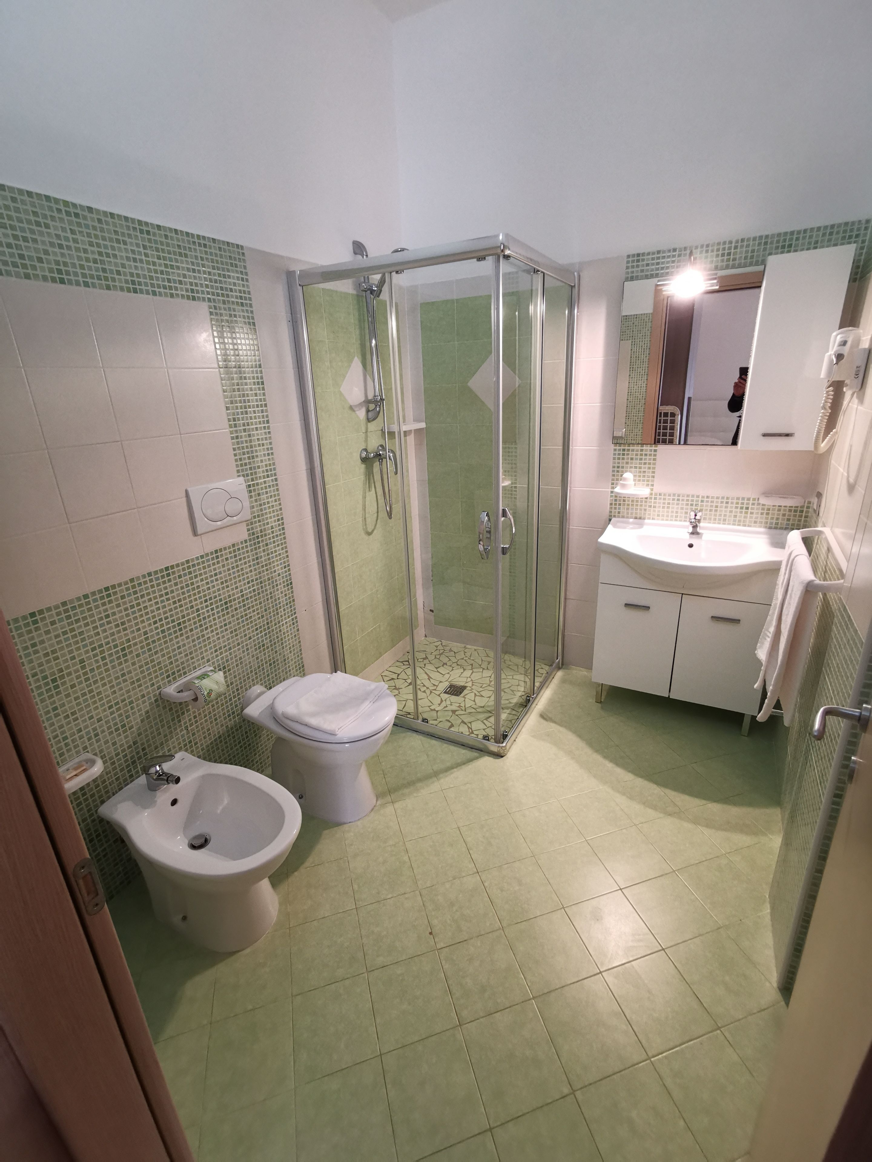 Ein Badezimmer mit Duschkabine, Bidet, Toilette, Waschbecken und Spiegel.