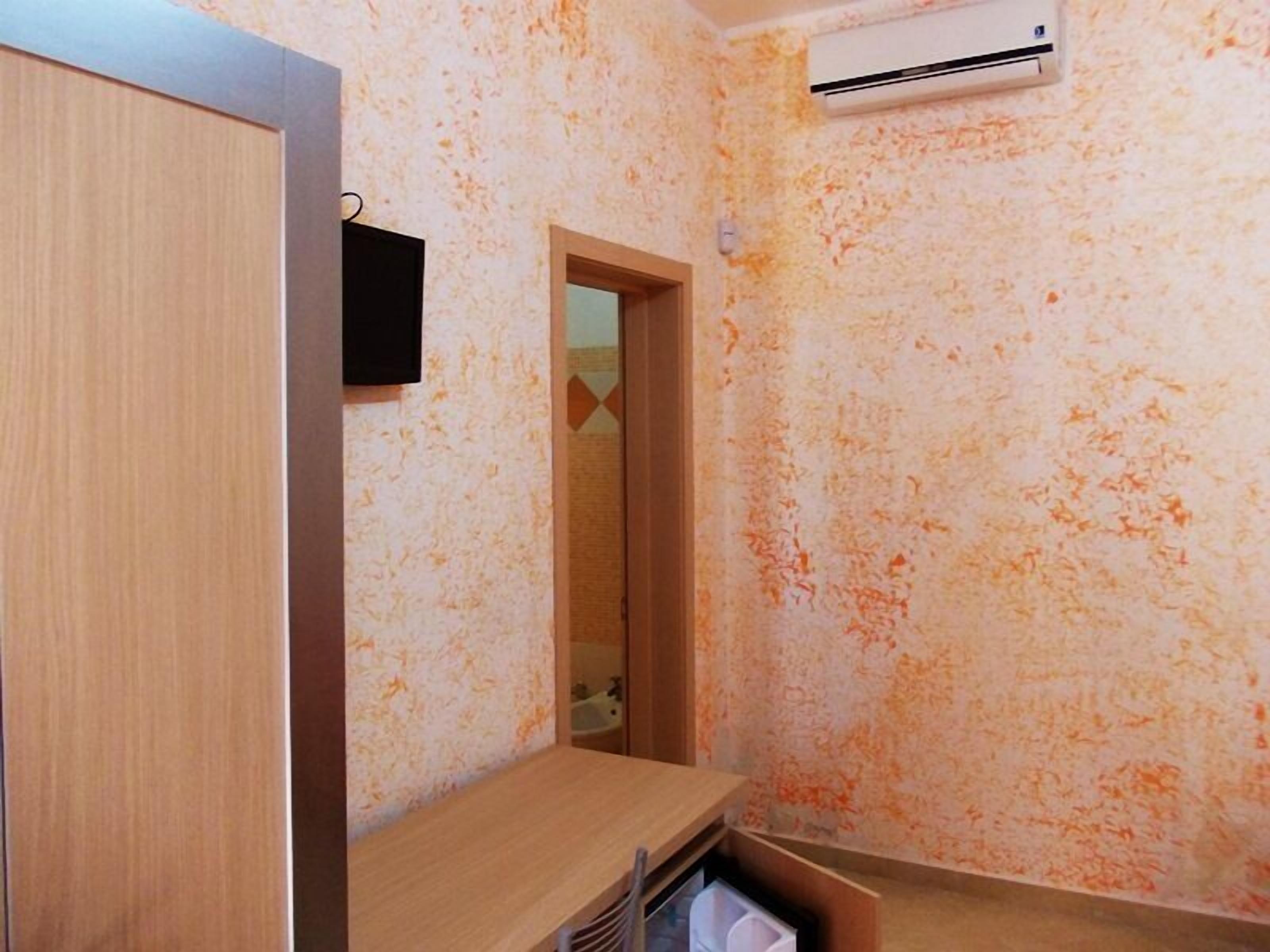 A bathroom with a wooden door, a mirror, a towel rack, and a wall-mounted air conditioner.