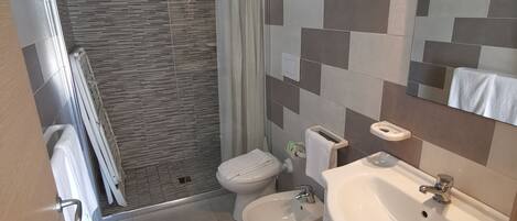 A modern bathroom with a shower, toilet, bidet, and sink.