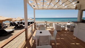 A beachside patio with outdoor seating, a view of the ocean, and a covered area with umbrellas. - Samanà Bed (Porto Cesareo)