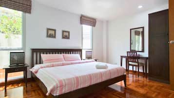 A bedroom with a wooden bed, a desk, a chair, and a wardrobe.