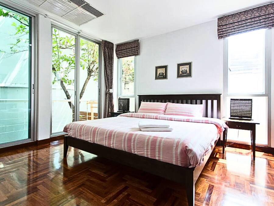 Un dormitorio con una cama grande, piso de madera y una puerta corrediza de vidrio que da a un espacio exterior.
