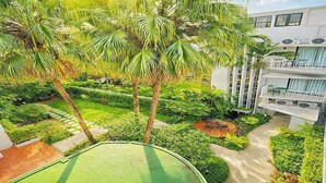 A modern building with multiple balconies, surrounded by lush greenery and palm trees. - Townhouse PK Garden (Bangkok)