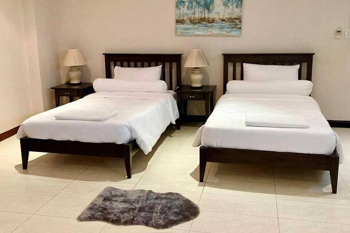 Hotellihuone, jossa on kaksi sänkyä, seinällä taulu ja lattialla matto.