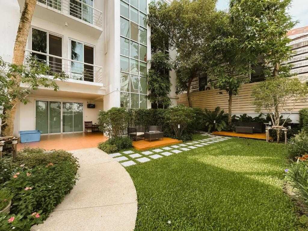 A courtyard with a lawn, seating area, and a building with large windows.