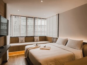 A modern hotel room with a large bed, a bench by the window, and a flat-screen TV. - Townhouse PK Garden (Bangkok)