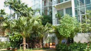 A modern building with large glass windows and a well-maintained garden with various plants. - Townhouse PK Garden (Bangkok)