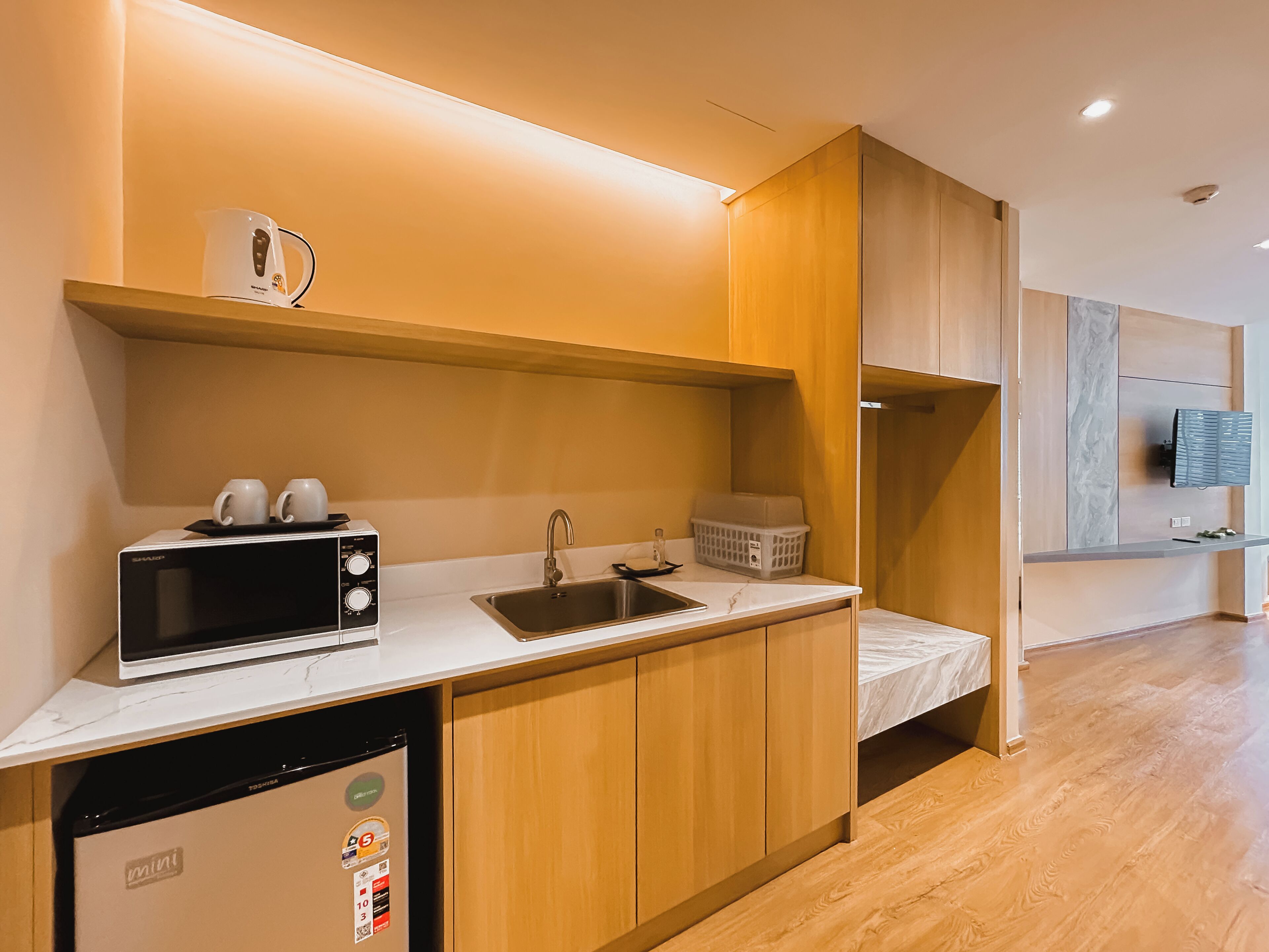 A compact kitchenette with a microwave, toaster, sink, and a mini refrigerator.