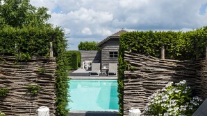 A backyard with a swimming pool, a wooden fence, and a lounge area with a table and chairs. - La Cereza (Oudenaarde)