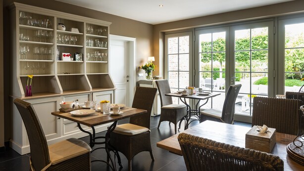 A dining area with wicker chairs, a wooden table, and a built-in wine rack. - La Cereza (Oudenaarde)