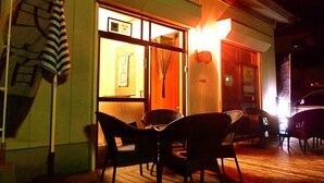 An outdoor seating area with wicker chairs and a wooden deck. - Aoshima Guesthouse Hooju - Hostel (Miyazaki)