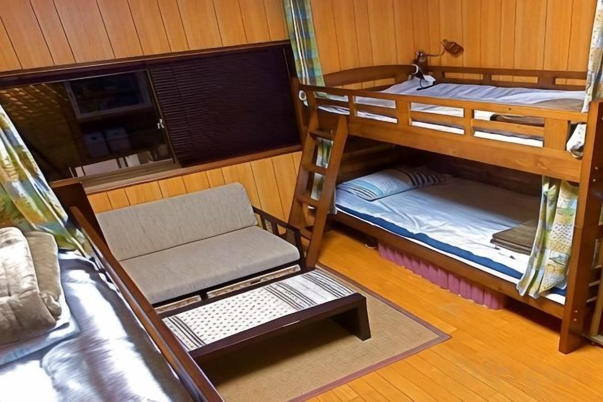A bunk bed room with a sofa and a window.