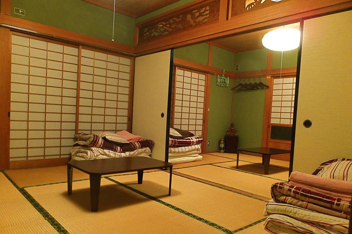 Een traditionele Japanse kamer met tatami vloerbedekking, een lage tafel en een bed met kussens.