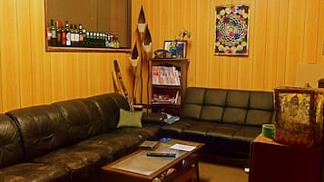 A living room with a leather couch, a coffee table, a bookshelf, and a painting on the wall.