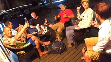 A group of people seated around a table on a wooden deck, engaged in conversation.