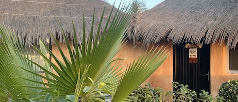 A thatched-roof building with a 'Spa' sign, surrounded by lush greenery.