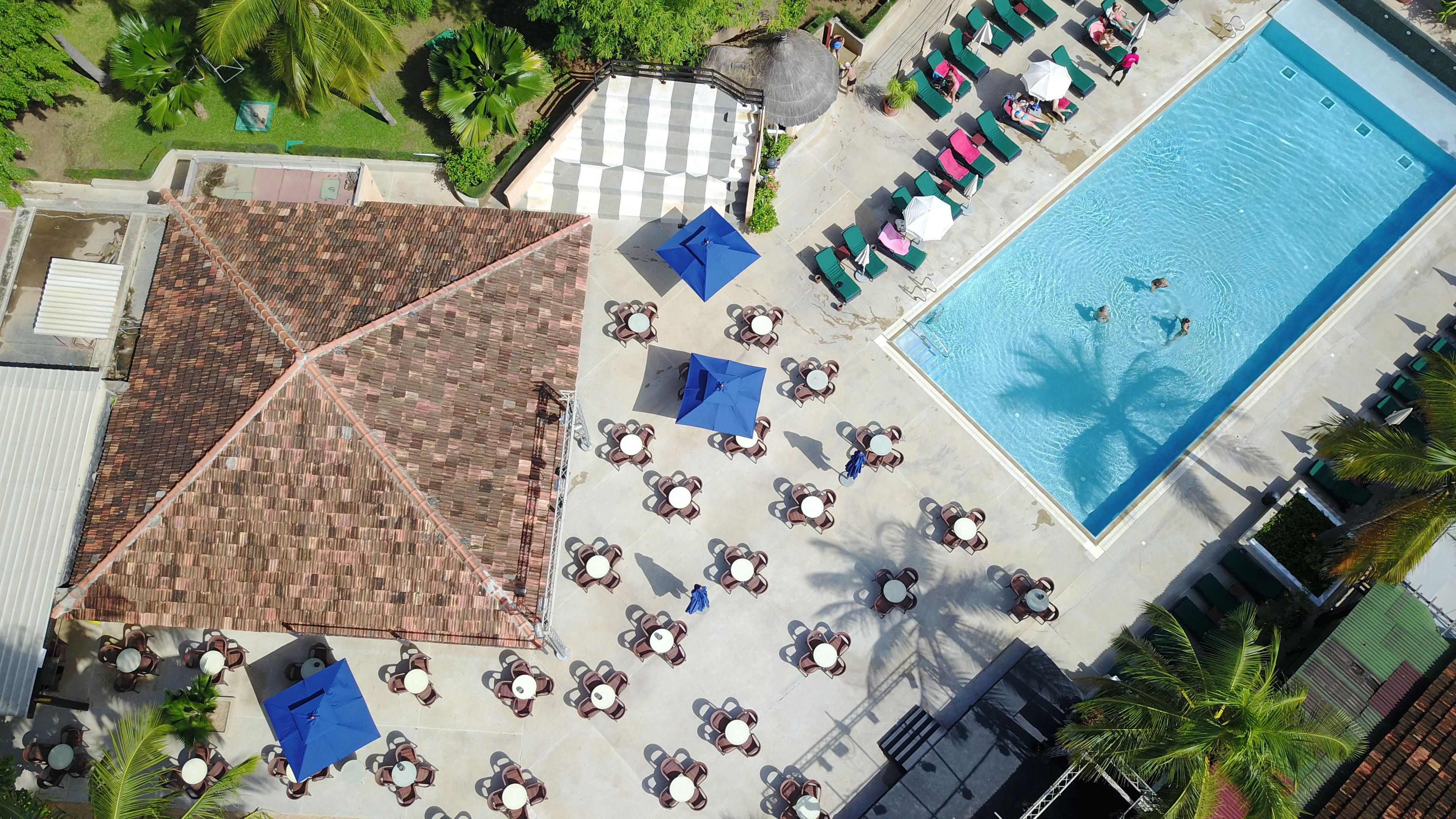 An aerial view of a resort with a swimming pool, lounge chairs, and a covered seating area.