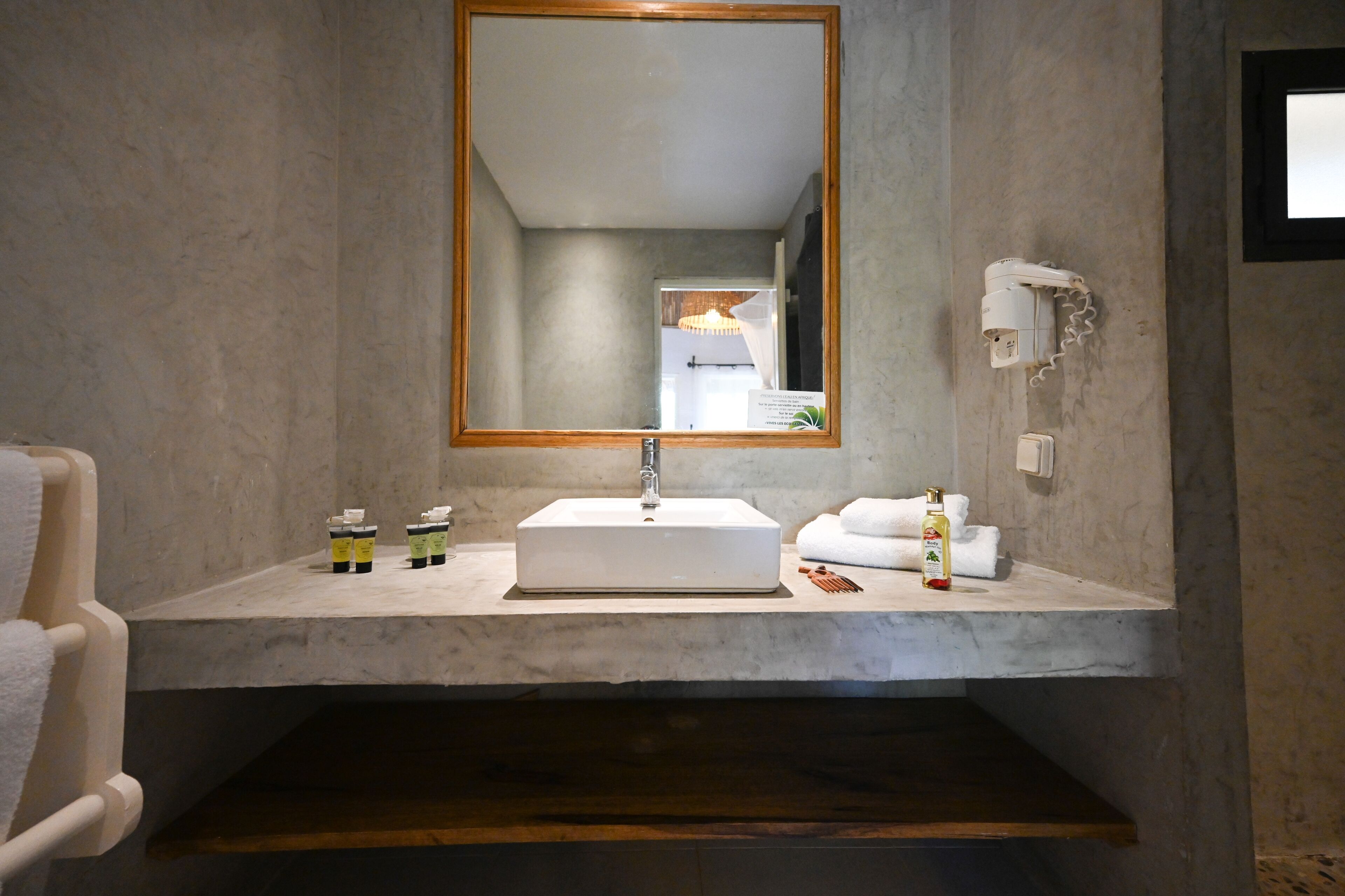 Un bagno con uno specchio grande, un lavandino bianco e un portascopevoli.