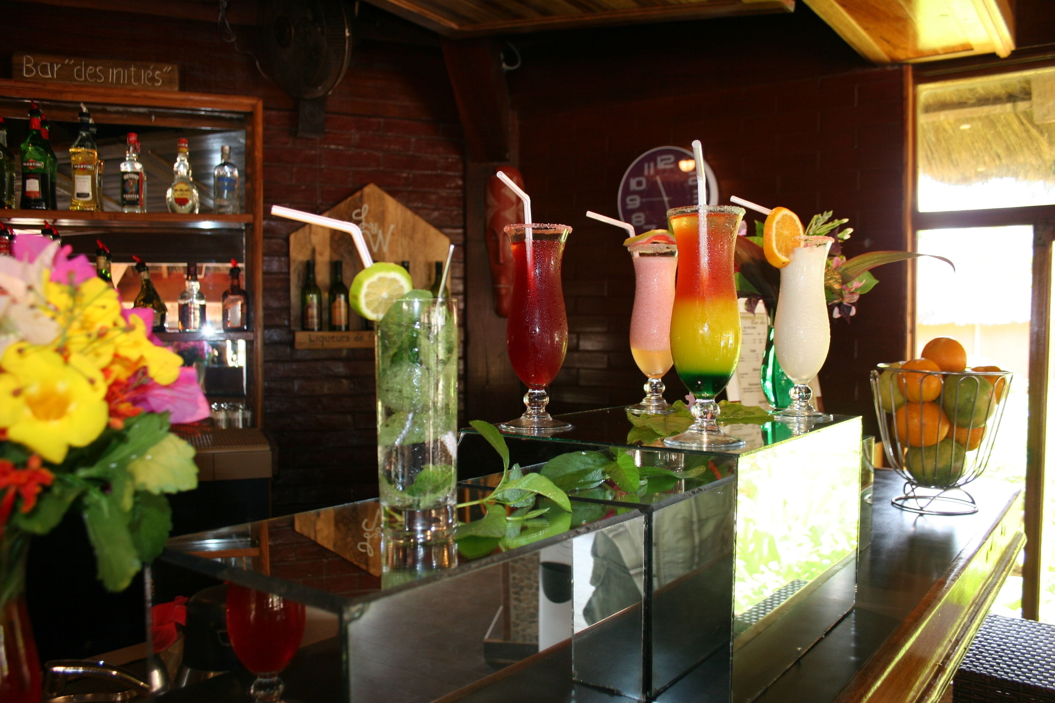 A bar with a variety of colorful drinks and a selection of bottles on shelves.