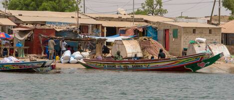 A boat with colorful decorations and text, docked near a building with a sign that reads "QUINCAILLERIE SERIE".