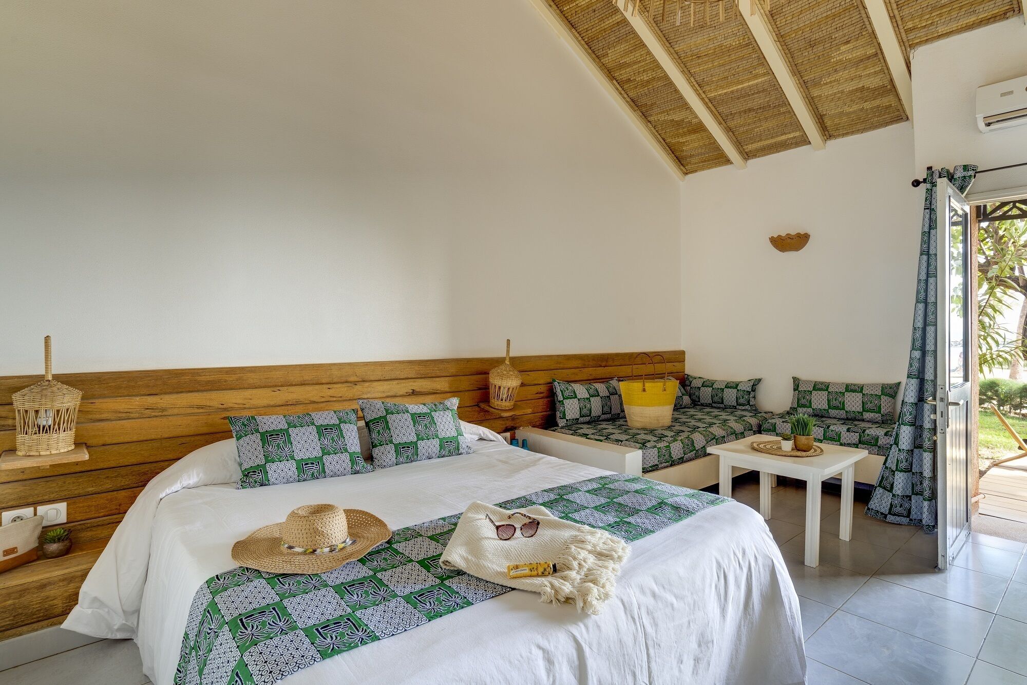Una habitación con cama, sofá, una mesita y ventana con cortinas.