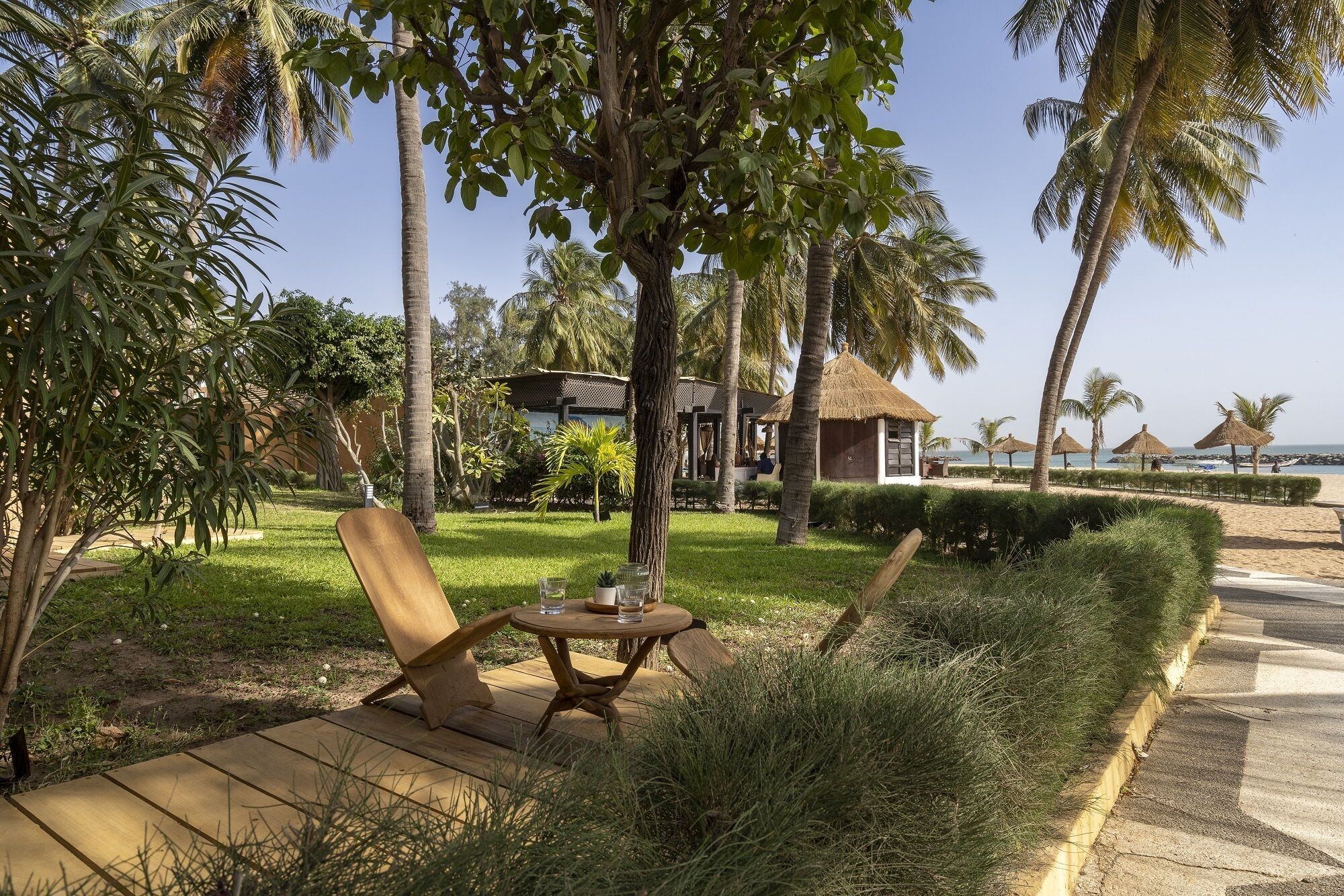 A tropical resort setting with a wooden deck, lounge chairs, and a thatched-roof hut.