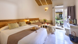 Quarto com cama grande, uma mesinha e luminária de palha no teto.