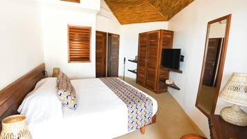 A bedroom with a bed, wooden wardrobe, television, and a mirror.