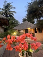 A thatched-roof building with a well-maintained garden and a wooden deck.