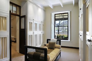 A hallway with a sofa, a window with a view, and white cabinetry.