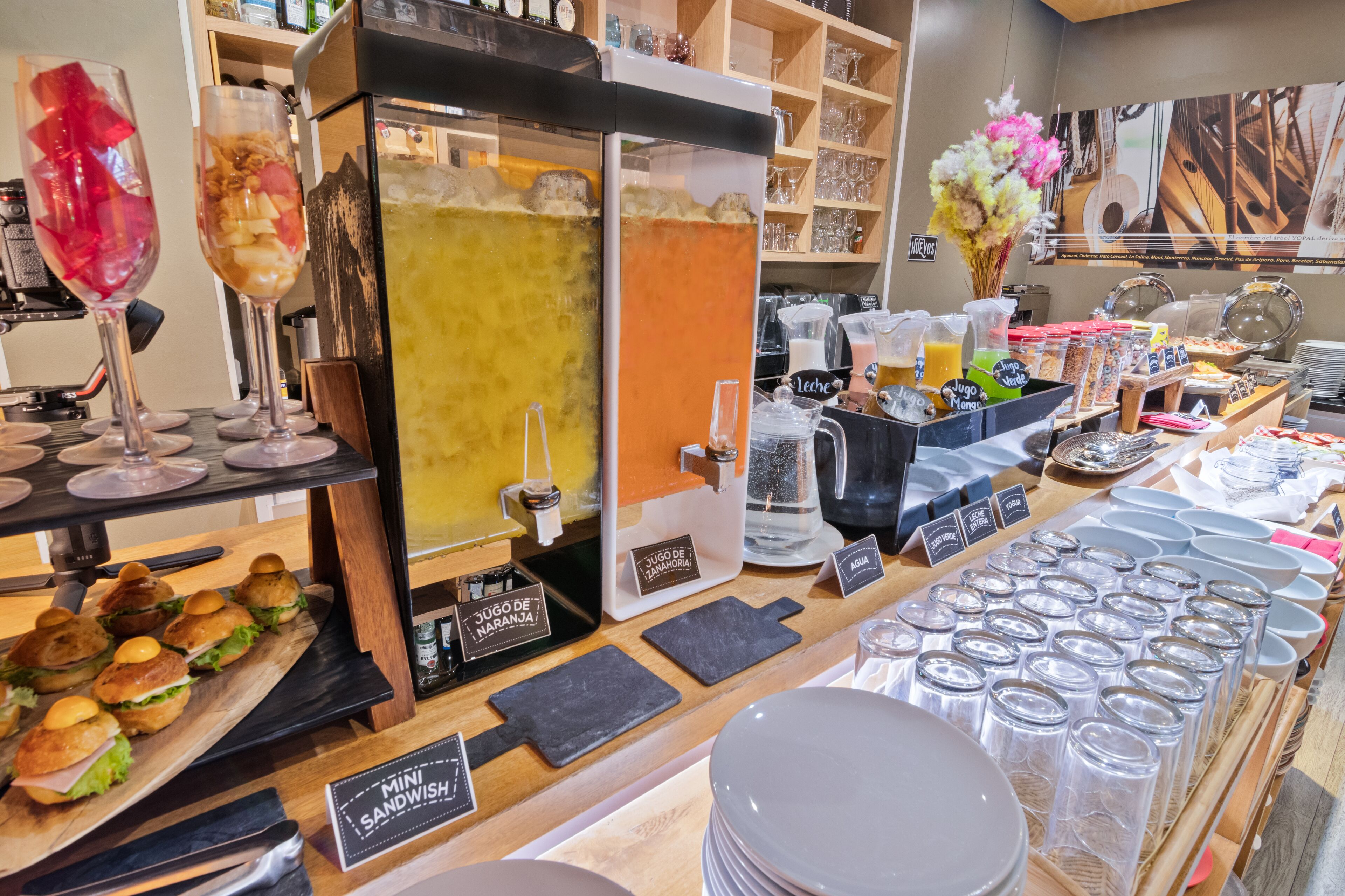 A café counter with a variety of food items, a coffee machine, and a selection of glasses and plates.