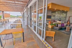 A spacious outdoor seating area with tables and chairs, large windows, and a view of the landscape. - GHL Style Yopal (Yopal)