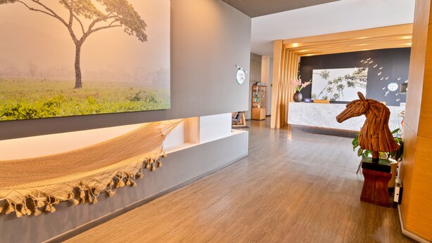 Un interior moderno con una hamaca, una escultura de caballo de madera y un cuadro de un árbol grande.