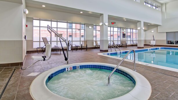 Una piscina interior con bañera de hidromasaje, zona de estar y vistas al exterior.