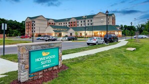 Un hotel grande con varias edificaciones, un letrero de Homewood Suites by Hilton y un estacionamiento con automóviles.