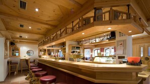 Un intérieur en bois avec un espace bar, plusieurs options d’aménagement pour s’asseoir et un escalier.