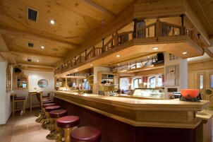 A wooden interior with a bar area, multiple seating options, and a staircase.