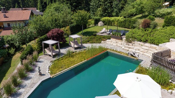 Une piscine avec une terrasse en bois, des chaises longues et des parasols.