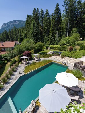 Une piscine avec une terrasse en bois, des chaises longues et des parasols.