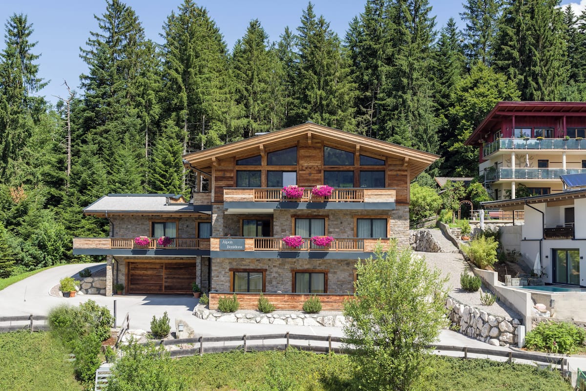 A multi-story building with a stone facade, wooden balconies, and a ski lift in the background.