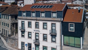 Un hotel con fachada blanca, varios balcones y paneles solares en el tejado.
