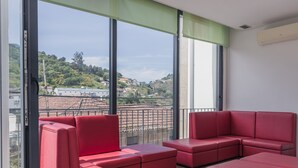 Un balcón con asientos tapizados en rojo y ventanas grandes que ofrecen vistas a una zona residencial.