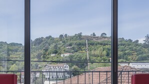 Un balcón con asientos acolchados rojos y vistas a una colina con edificios.