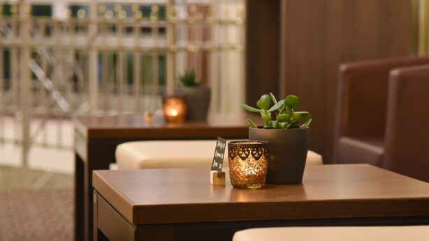 A wooden table with a potted plant and a candle. - Hotel Säntis (Munich)