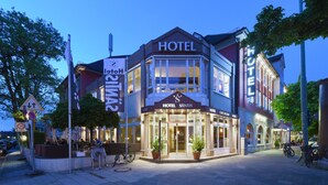 A hotel with a prominent entrance, a cafe, and outdoor seating. - Hotel Säntis (Munich)
