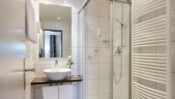 A modern bathroom with a glass-enclosed shower, a white sink, and a toilet.