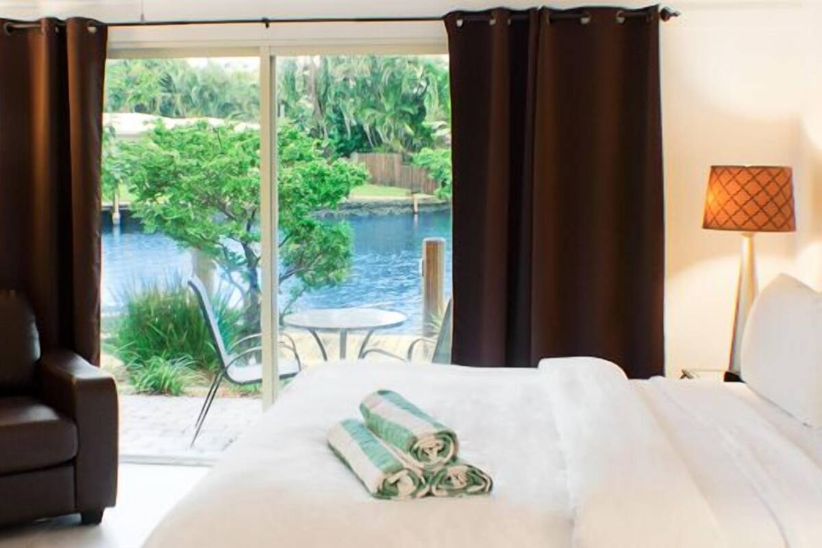 Camera d'albergo con un letto, una sedia, un tavolo e vista sulla piscina e sul verde.